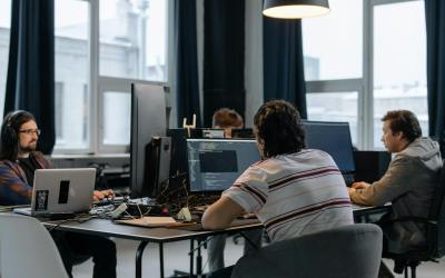 men sitting at the desks in an office and using computers