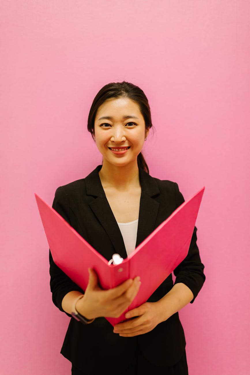 a woman wearing a blazer holding a binder